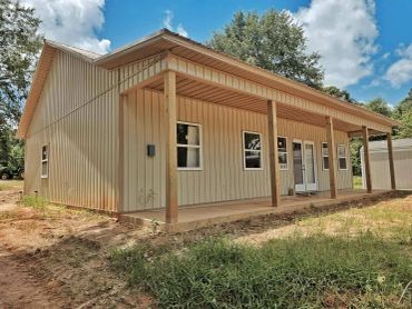 A beige metal building with a covered porch under a blue sky.
