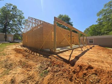 Wooden house frame under construction on a sunny day.