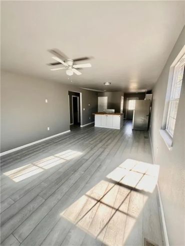 Bright, empty open-concept room with gray walls and light wood flooring.