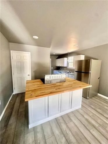 Modern kitchen with wooden island countertop and stainless steel appliances.