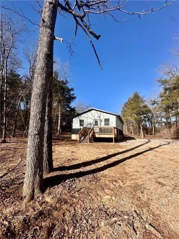 Small house surrounded by trees under a clear blue sky.