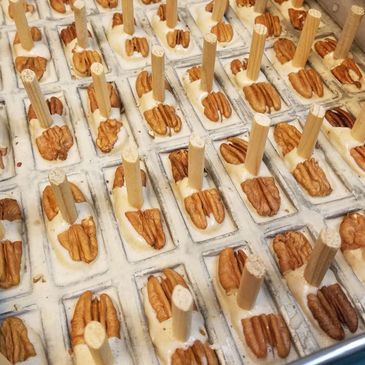 Rows of pecan popsicles being prepared in molds with wooden sticks.