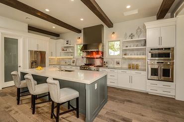 Modern kitchen with white cabinets, wooden beams, and a large island with seating.