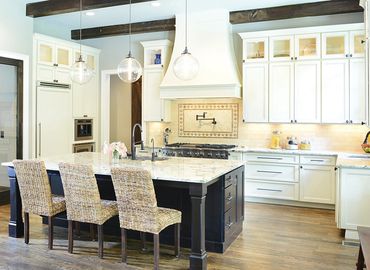 Bright modern kitchen with marble island and wicker chairs.