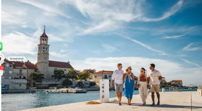 Two couples strolling along a sunny waterfront boardwalk at a domestic cruise port.