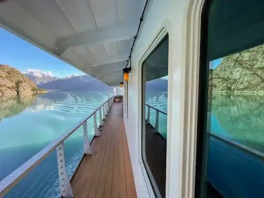 Scenic view from a boat on calm water surrounded by rocky mountains.