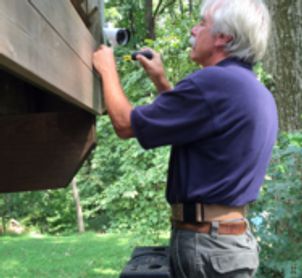 a man installing a camera on the side of a house