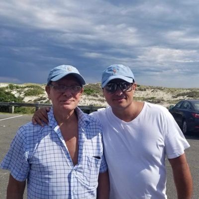 Two men wearing blue caps posing outdoors.