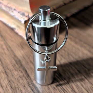 Small metal anointing oil vial with Holy Cross pendant.