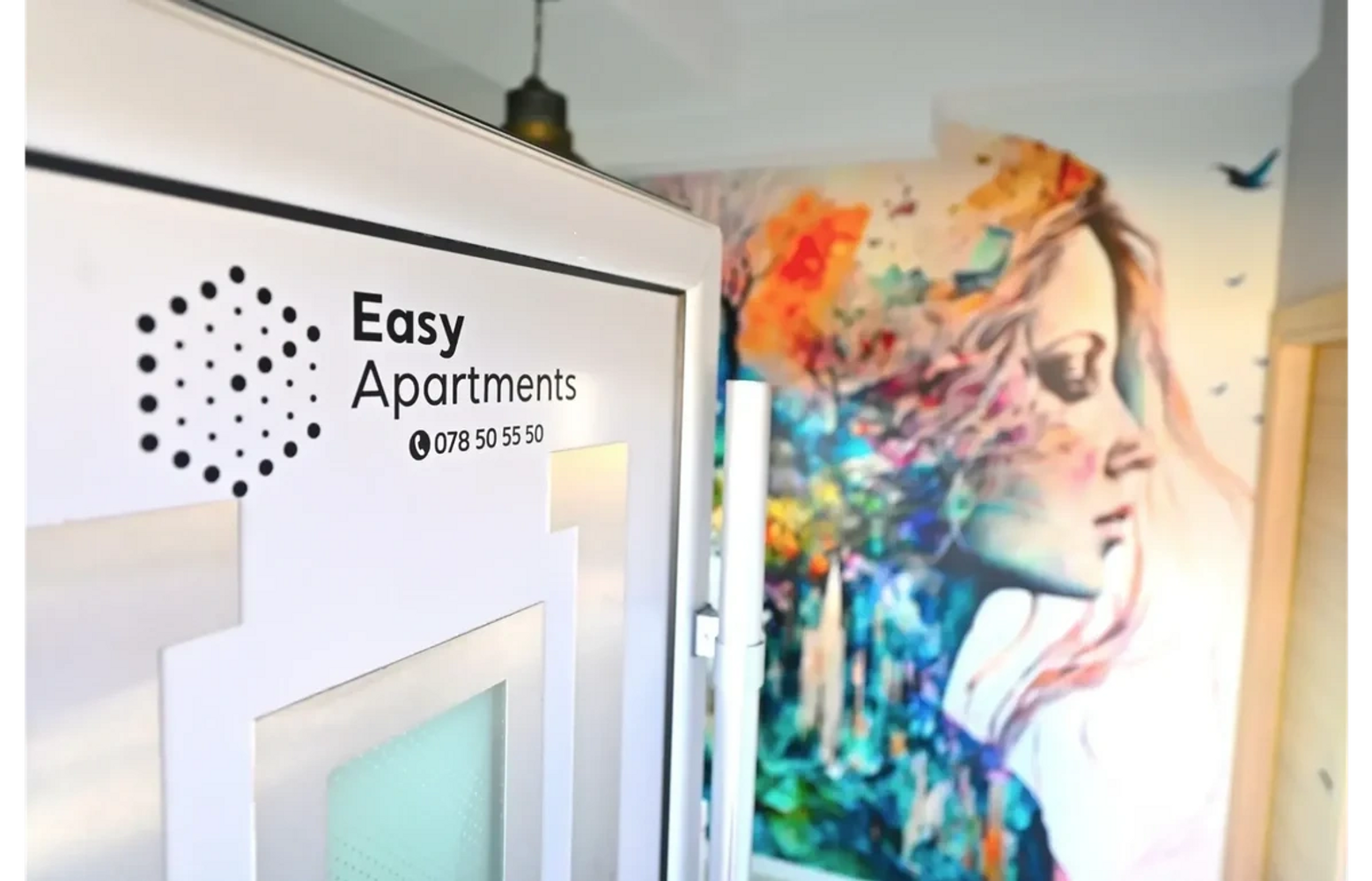 "Entrance of Easy Apartments with visible logo and a colourful artistic mural of a woman's profile"