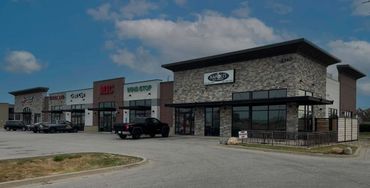 Strip mall with various businesses and clear blue sky.