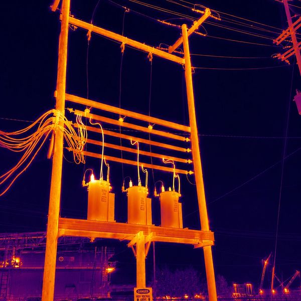 Thermal image of an electrical transformer on a utility pole at night.