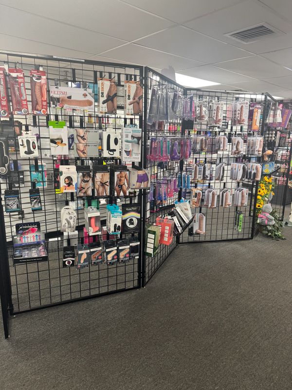 Display of adult toys and accessories on black grid panels in a store.