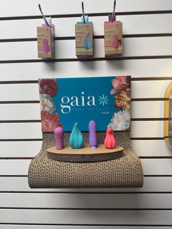 Display of colorful Gaia eco-friendly personal care products on a cardboard stand.