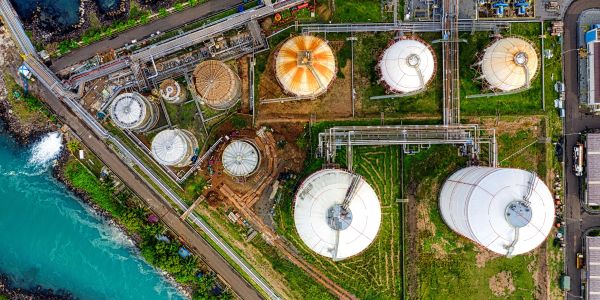 Aerial view of industrial tanks by a coastal area.
