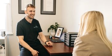 Tim the podiatrist talking to a happy patient about their successful outcome