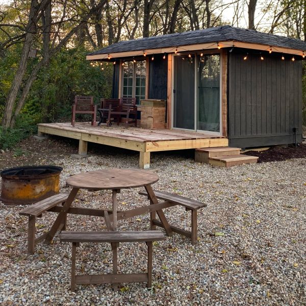 Small cabin with a wooden deck and picnic table.
