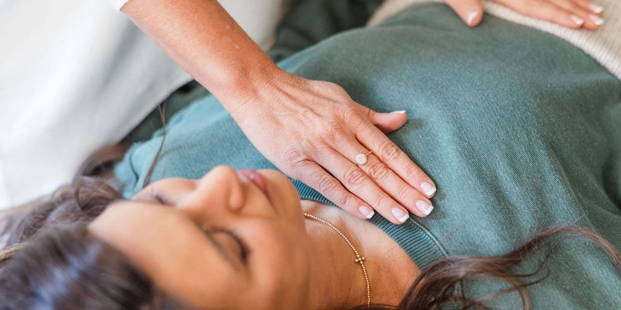A woman rests with a hand gently placed on her chest.