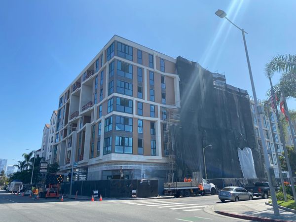 A modern multi-story building under construction on a sunny day.