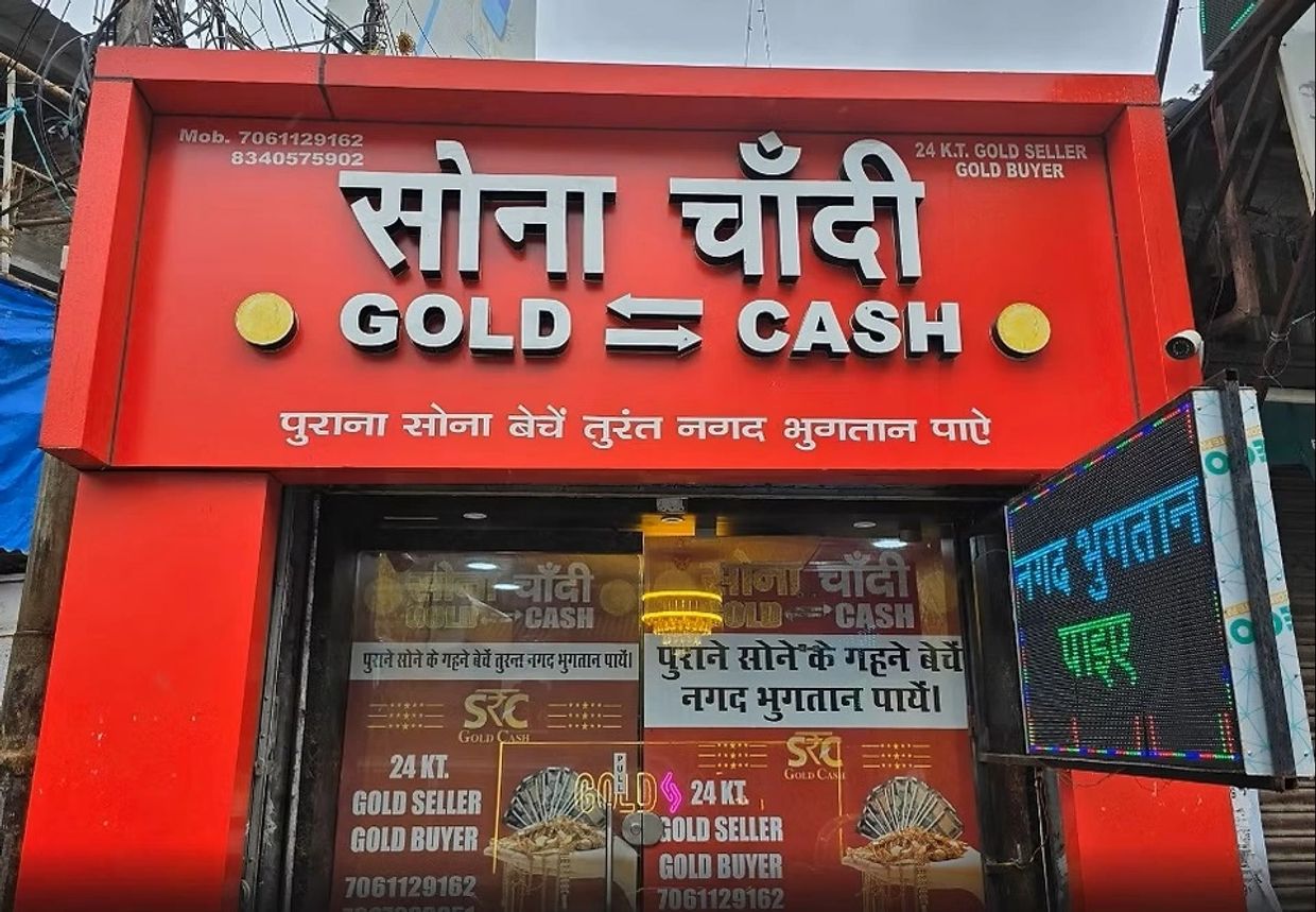 Red shopfront offering gold to cash exchange services in Hindi and English.