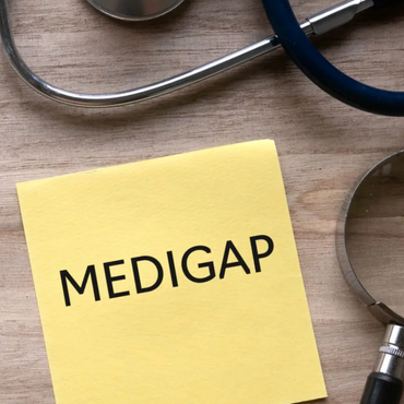 IMAGE OF A YELLOW NOTE, READING "MEDIGAP" ON A WOODEN TABLE, NEXT TO A MAGNIFYING GLASS