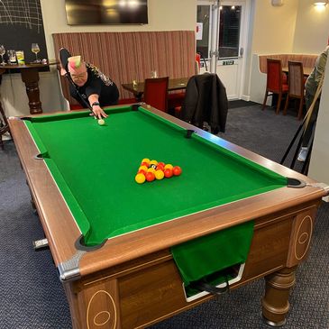 Person aiming to strike balls on a green pool table in a cozy room.