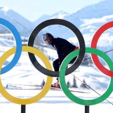 Skier framed by Olympic rings on snowy mountain.