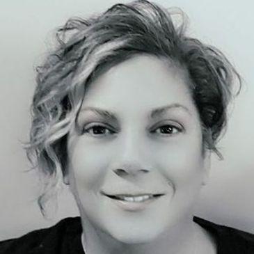 Black and white portrait of a smiling woman with curly hair.