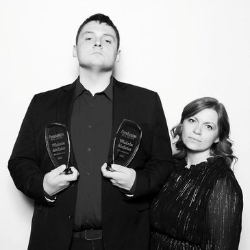 Two individuals posing with awards at the Pemberton Real Estate holiday party.