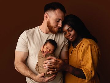 A loving couple cradling their newborn baby by a Maricopa newborn photographer.