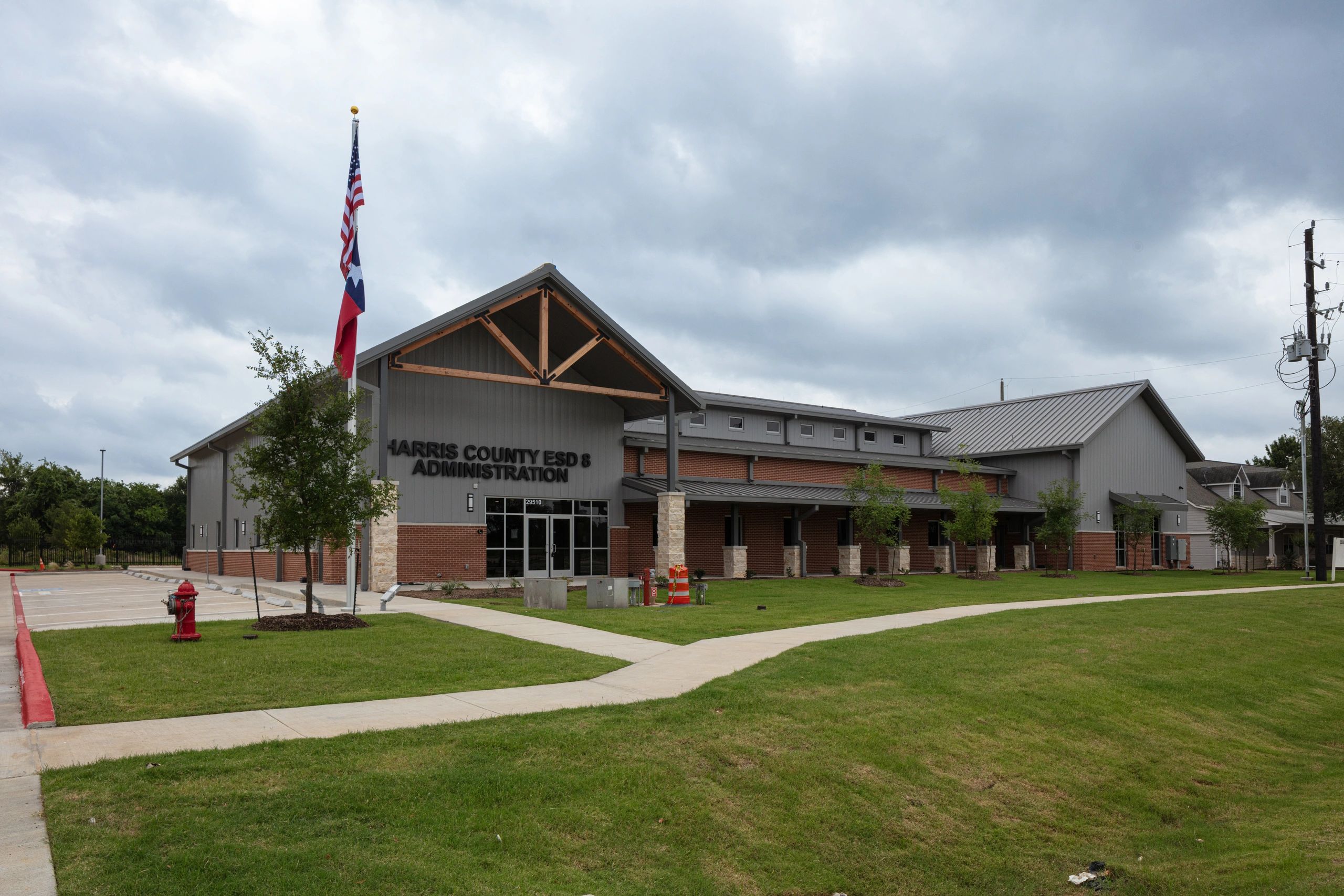 Modern Harris County administration building with flags and cloudy sky.
