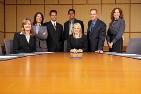A diverse group of seven professionals posing in a conference room.