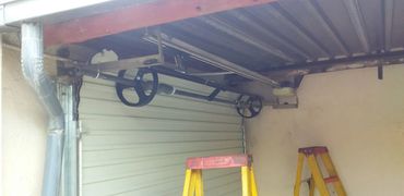 Partially open garage door with mechanical pulleys and ladders.