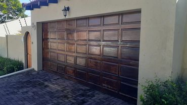 Wooden garage door with a small adjacent door on a beige house.