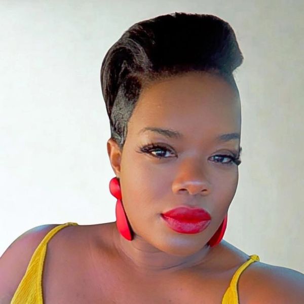 Woman with bold red lipstick and earrings posing confidently.
