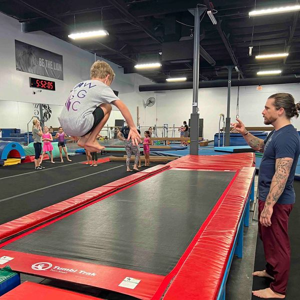 Young boy on trampoline receives encouragement from his coach