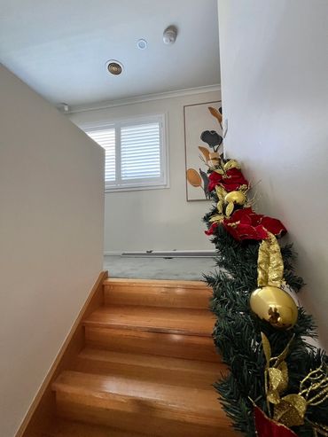 A stairway landing with plantation shutters installed on the window, allowing soft natural light wh