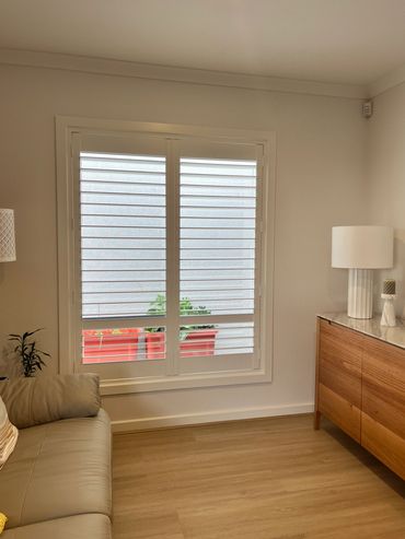 A living room with a two-panel window featuring plantation shutters,