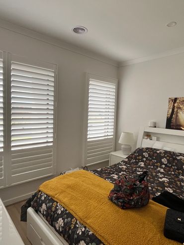 A bedroom windows fitted with plantation shutters, allowing soft light while maintaining privacy