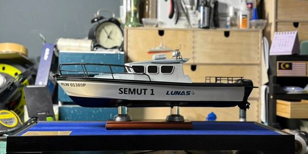 A detailed model boat named SEMUT 1 displayed indoors on a stand.