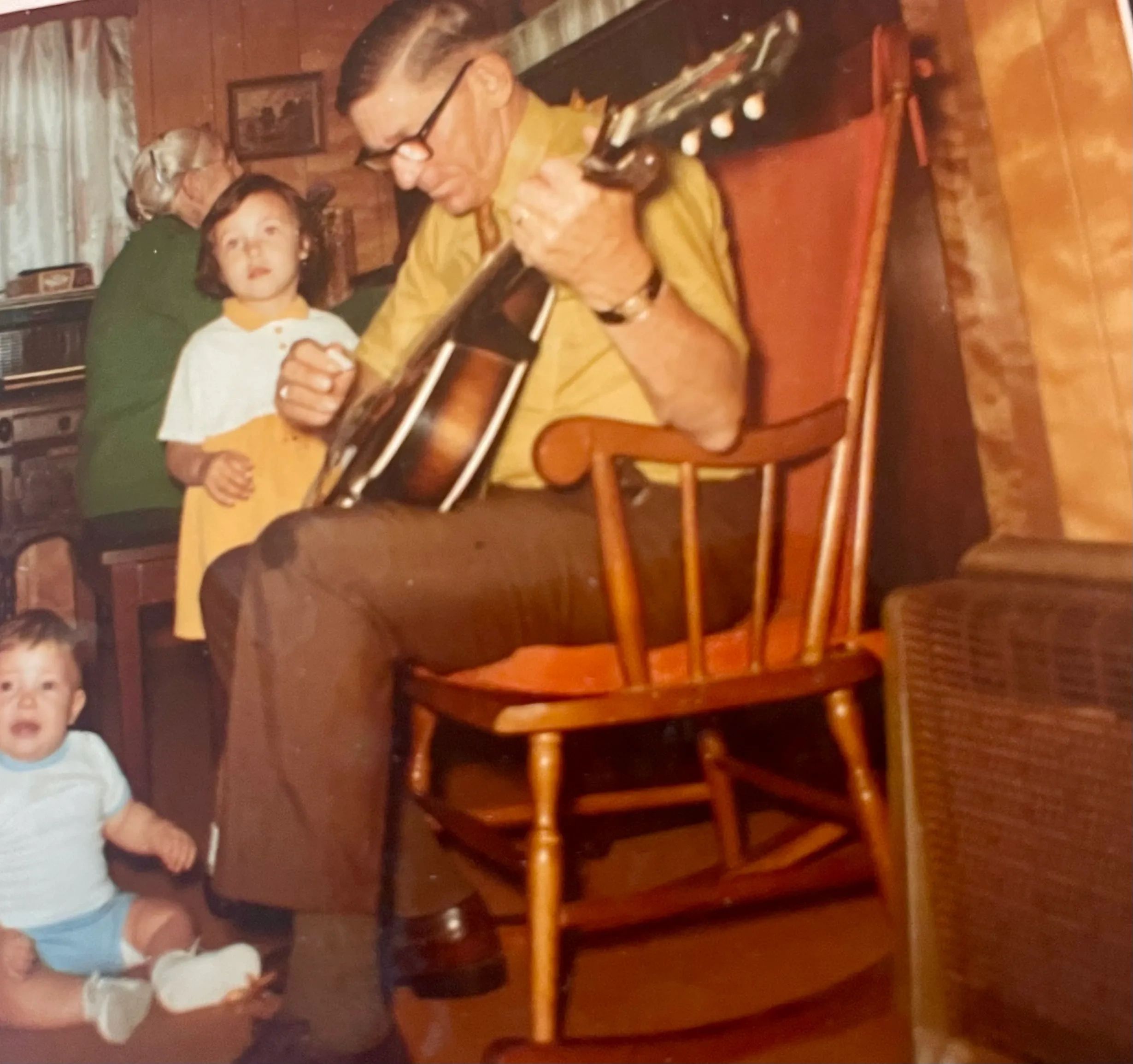 Dale Lowe playing guitar, Nova Lowe on piano, with grandchildren