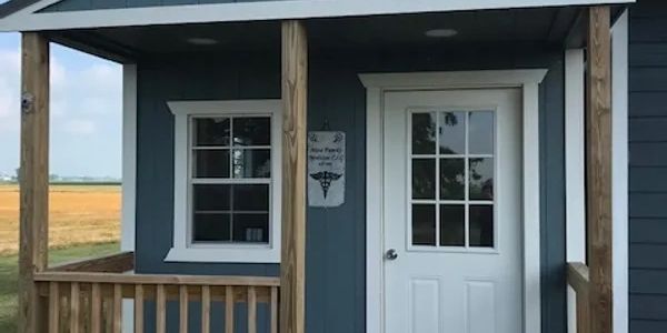 Small blue medical office with white door and porch.