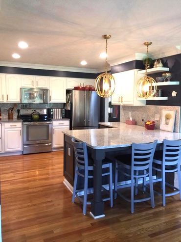 Modern kitchen with white cabinets, stainless steel appliances, and a large island with pendant lighting.