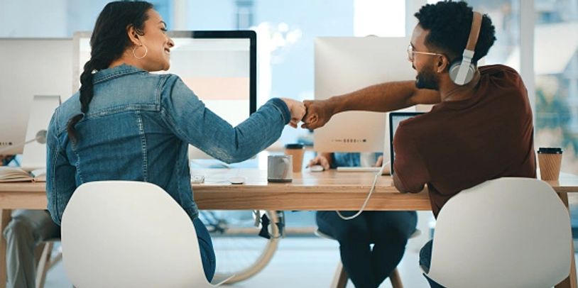 Two happy, engaged colleagues fist-bumping