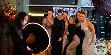 Group of ladies at an elegant gala getting their picture taken by the roamer booth