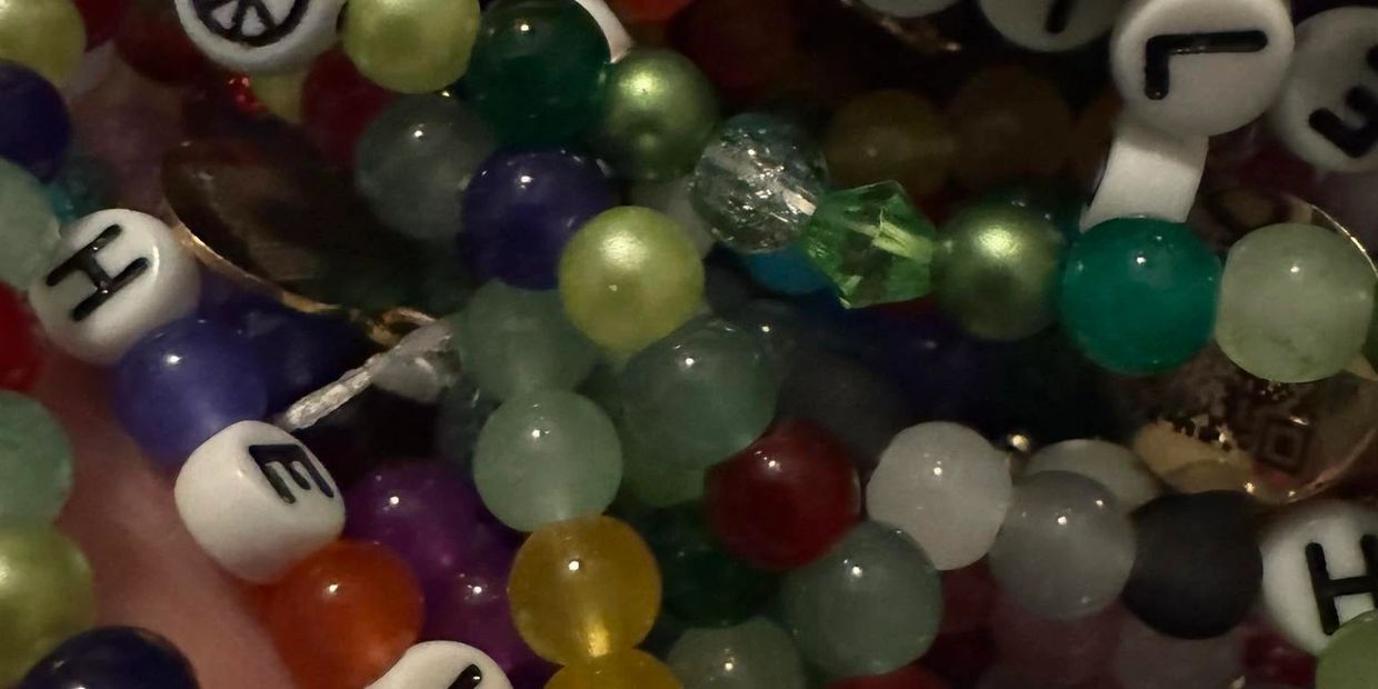 Close-up of colorful beaded bracelets with lettered and patterned beads.