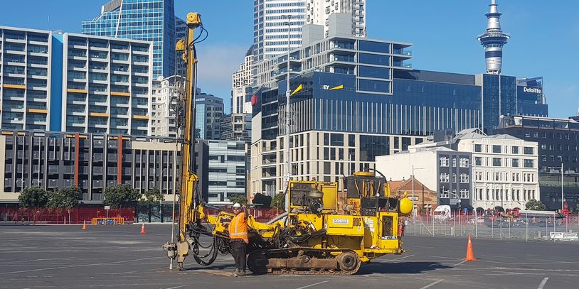 Worker with yellow drilling machine in urban area.