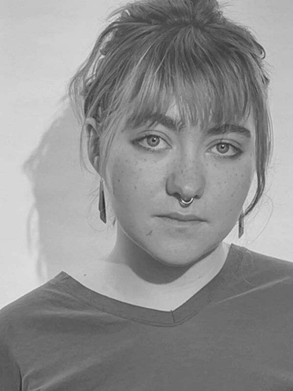 Black and white portrait of a young woman with freckles and a septum ring.