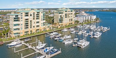 Marina with boats docked beside residential buildings on a sunny day.
