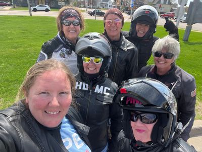 Group of women motorcyclists smiling outdoors.